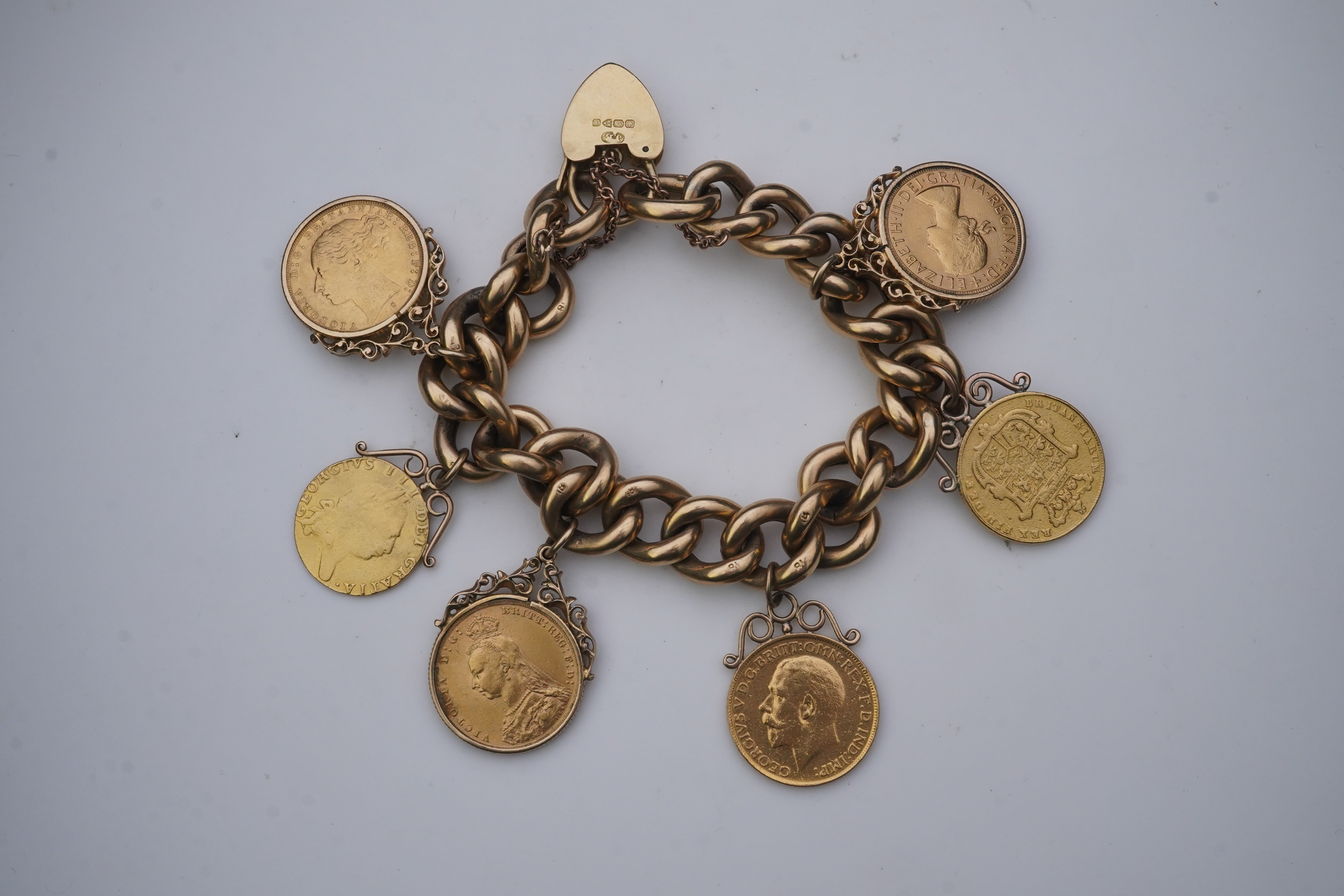 An Edwardian 18ct gold charm bracelet and five gold coin pendants